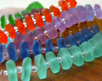May include: A colorful beaded necklace made of frosted glass beads in shades of green, blue, purple, orange, and red. The beads are strung on a clear thread.