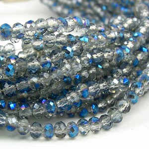 May include: A strand of faceted glass beads in shades of clear and blue. The beads have an iridescent finish, creating a shimmering effect.