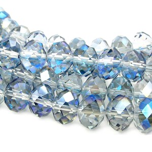 May include: A strand of faceted glass beads in shades of blue and clear. The beads have a iridescent finish.