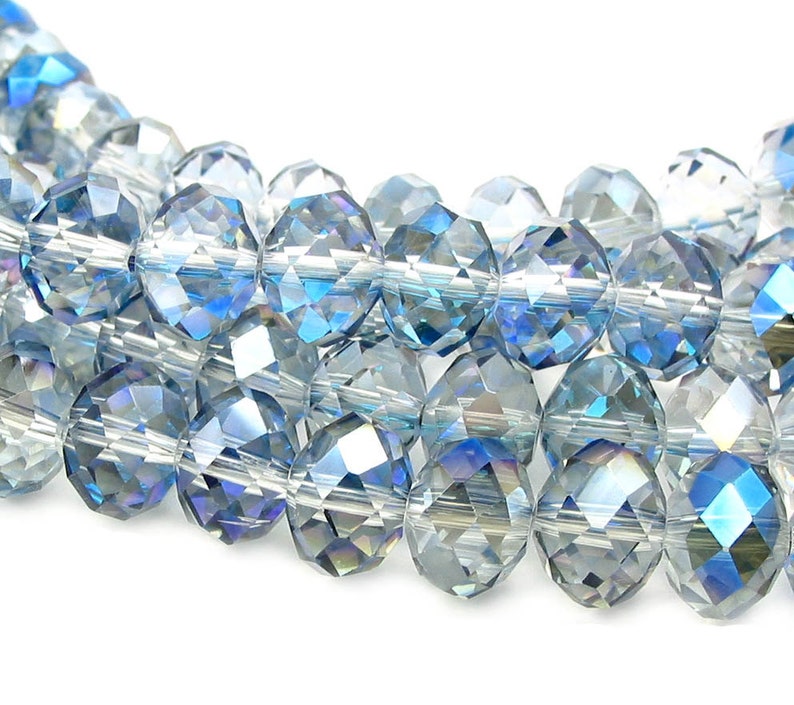 May include: A strand of faceted glass beads in shades of blue and clear. The beads have a iridescent finish.