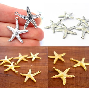 May include: A collection of silver and gold starfish charms with a textured surface. The charms have a loop at the top for attaching to jewelry or other crafts.