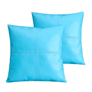 May include: Two square, light blue throw pillows. Each pillow has a stitched cross pattern in the center. The pillows are made of a smooth, solid-colored material and are set against a white background.