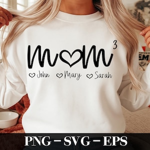 以下が含まれることがあります： 白いスウェットシャツに、黒い文字で「Mom 3」と書いてあり、3つのハートと、その下にジョン、メアリー、サラの名前が書かれています。