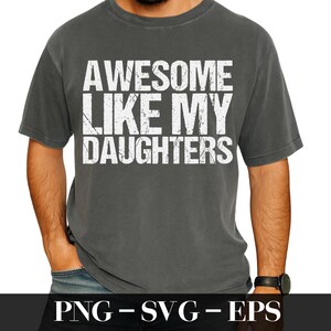 Op de afbeelding: Donkergrijs t-shirt met de tekst "AWESOME LIKE MY DAUGHTERS" in versleten witte letters. Het shirt heeft een ronde hals en korte mouwen. De afbeelding bevat ook de tekst "PNG - SVG - EPS".
