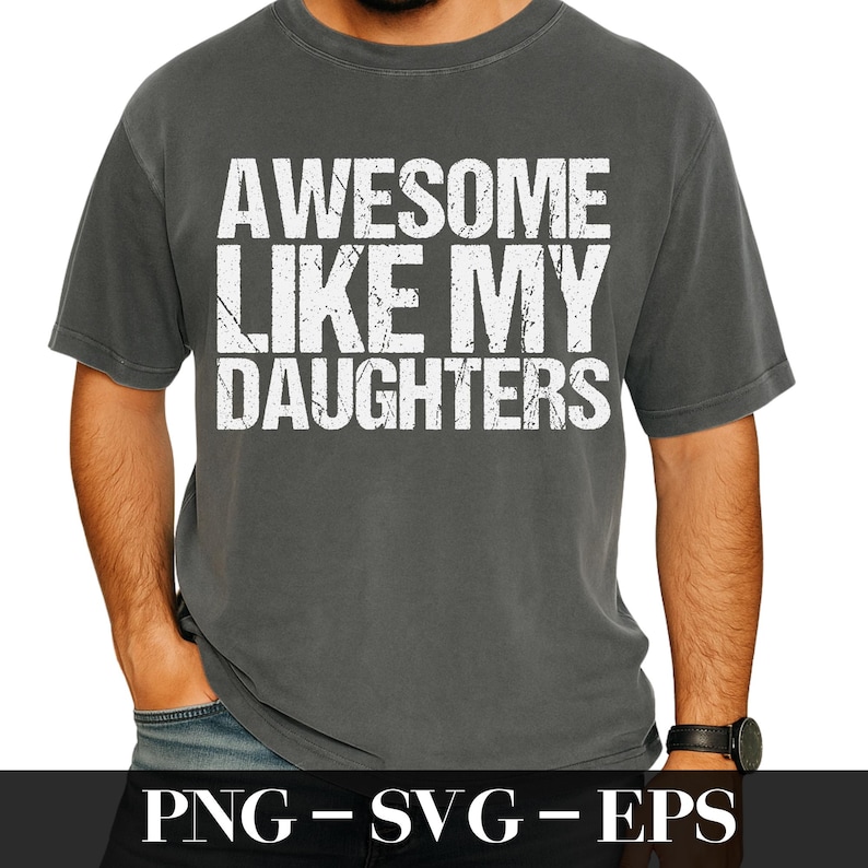 Op de afbeelding: Donkergrijs t-shirt met de tekst "AWESOME LIKE MY DAUGHTERS" in versleten witte letters. Het shirt heeft een ronde hals en korte mouwen. De afbeelding bevat ook de tekst "PNG - SVG - EPS".
