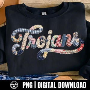 May include: Navy blue sweatshirt with the word "Trojans" in a patchwork design. The letters are made of various patterned fabrics, including gingham, floral, and polka dots. The sweatshirt is a Gildan brand.