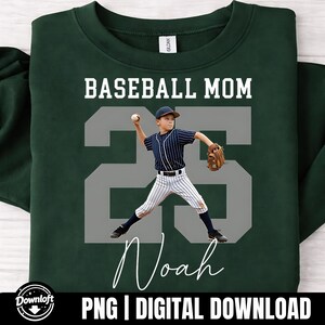 May include: Dark green sweatshirt featuring the text "BASEBALL MOM" above a grey number "25" and the name "Noah" in white script. The number "25" has a photo of a boy in a baseball uniform. The bottom of the sweatshirt has the text "PNG | DIGITAL DOWNLOAD".