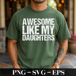 Op de afbeelding: Een groen t-shirt met de tekst "AWESOME LIKE MY DAUGHTERS" in verweerde witte letters. Het shirt heeft een ronde hals en lijkt gemaakt van een zacht materiaal. De onderkant van de afbeelding bevat de tekst "PNG - SVG - EPS".