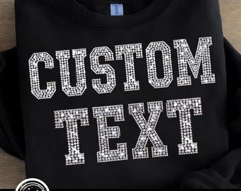 May include: Black sweatshirt with the words "CUSTOM TEXT" in large, sparkling, rhinestone-style letters. The design is centered on the front of the garment. The bottom of the image includes the text "PNG | DIGITAL DOWNLOAD".