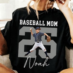 A digital download mockup featuring a white t-shirt with a vintage sketch of a youth baseball player swinging a bat, layered over a large custom grey block number 55, with Baseball Mom at the top and a custom name at the bottom.