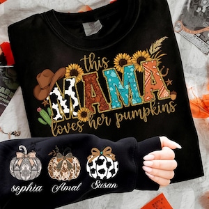 Puede incluir: Sudadera negra con el texto "this MAMA loves her pumpkins" en una fuente decorativa. La palabra "MAMA" está diseñada con un estampado de vaca, floral y turquesa. Una segunda sudadera negra muestra tres diseños de calabaza con nombres.