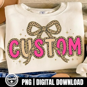 May include: Cream-colored sweatshirt with the word "CUSTOM" in a pink and leopard print design. A leopard print bow is above the word, and gold stars are scattered around the design. The bottom of the image shows the text "PNG | DIGITAL DOWNLOAD".