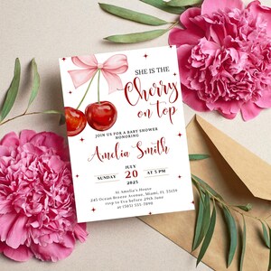 K&ouml;nnte beinhalten: Eine wei&szlig;e Babyparty-Einladung mit einem roten Kirsch-Design auf der Oberseite. Die Einladung lautet "She is the Cherry on Top" und enth&auml;lt den Namen "Amelia Smith". Datum und Uhrzeit der Party sind Sonntag, der 20. Juli 2025, um 15:00 Uhr. Die Einladung enth&auml;lt auch die Adresse und RSVP-Informationen.