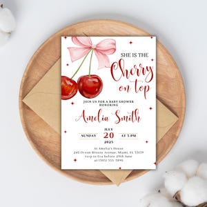 K&ouml;nnte beinhalten: Eine Babyparty-Einladung mit einem Kirsch-Design. Die Einladung ist wei&szlig; mit roten und rosa Akzenten. Sie lautet "Sie ist die Kirsche auf dem Kuchen" und enth&auml;lt den Namen Amelia Smith, das Datum 20. Juli 2025 und die Uhrzeit 15:00 Uhr. Die Einladung enth&auml;lt auch die Adresse und die RSVP-Informationen.