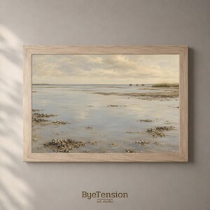 Op de afbeelding: Een landschapsschilderij in een lichthouten lijst met een rustig kusttafereel met ondiep water, zandvlaktes en verspreide rotsen onder een bewolkte lucht. De tekst ByeTension art studio staat onder het ingelijste kunstwerk gedrukt.