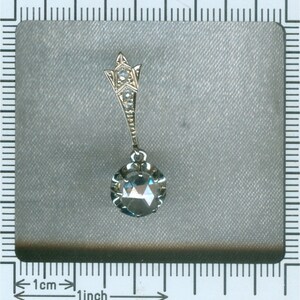 May include: A silver pendant with a large, clear, faceted gemstone. The pendant is attached to a delicate chain with a small, star-shaped design at the top.