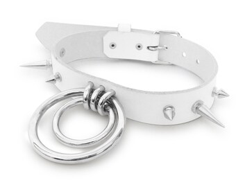 May include: White leather choker with silver spikes and a double ring pendant.