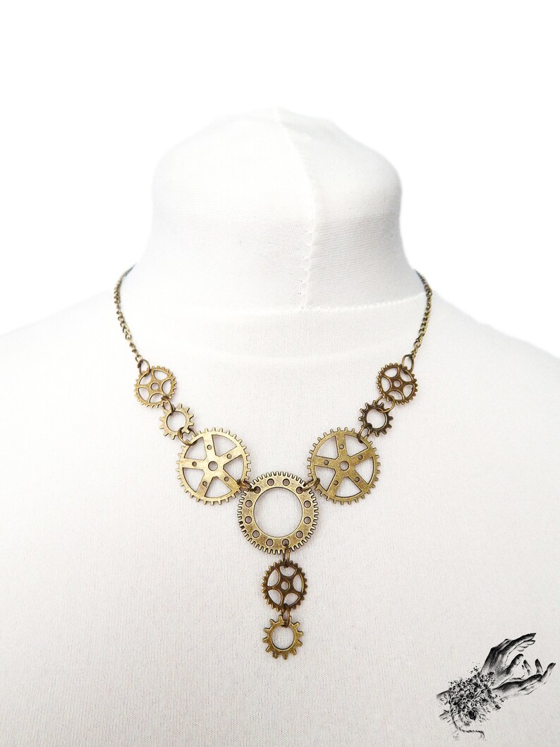 Unique handmade Steampunk necklace featuring intricately detailed bronze-tone gears and cogs. Suspended on a white mannequin bust, this bold necklace highlights its intricate links and clockwork inspired design. This handmade necklace showcases a vintage industrial aesthetic, perfect for steampunk enthusiasts and mechanical-inspired fashion lovers