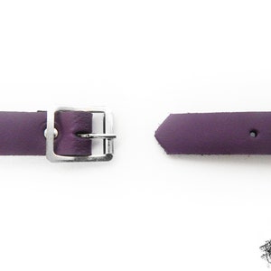 A photo of the back of the purple leather O ring wristband - one end has a silver coloured buckle, and the other end has multiple holes to fit 16cm to 21cm wrist circumference.