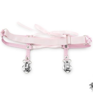 Rear view of a pink corset lacing thigh garter, showing the stretchy pink elastic strap with slider adjustment, ensuring a comfortable and versatile fit. Perfect for pastel goth, kawaii and Japanese fashion lovers, this pink thigh garter makes a bold addition to alternative fashion wardrobes. It is also an alternative option for bridal garters and alternative weddings, making a bold and unique statement on your special day. Displayed on a white background.