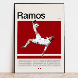 May include: A black and white poster with a red background featuring a soccer player in mid-air, kicking a soccer ball. The poster has the text "Real Madrid CF" and "Ramos /1986" printed on it.
