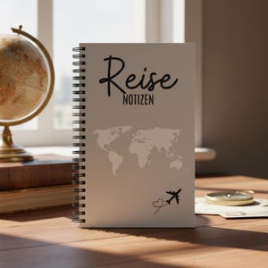 Könnte beinhalten: Ein Spiralnotizbuch mit den deutschen Worten "Reise Notizen" in schwarzer Schrift. Das Notizbuch zeigt eine Weltkarten-Grafik und eine kleine Flugzeug-Illustration mit einer gepunkteten Herzspur. Das Notizbuch liegt auf einer Holzoberfläche.