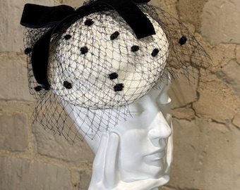 Tocado color marfil con lunares negros y lazo de terciopelo para el Día de las Damas de Ascot.