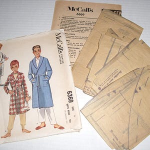 May include: A vintage McCall's sewing pattern for boys' robes, size 50. The pattern envelope features illustrations of boys in robes, with the number 6369. Includes pattern pieces and instructions.