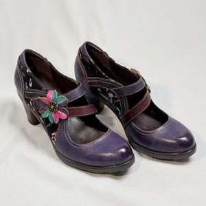 Peut inclure: Une paire de chaussures à talons violets avec un motif floral et une bride sur le pied.