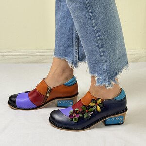 Puede incluir: Un par de zapatos de cuero coloridos con un dise&ntilde;o floral. Los zapatos tienen un esquema de color azul, morado, naranja y rojo. Los zapatos tienen un tac&oacute;n peque&ntilde;o y una cremallera en el lateral.