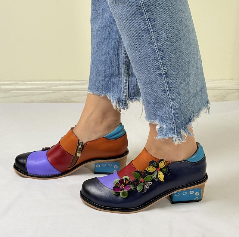 Puede incluir: Un par de zapatos de cuero coloridos con un dise&ntilde;o floral. Los zapatos tienen un esquema de color azul, morado, naranja y rojo. Los zapatos tienen un tac&oacute;n peque&ntilde;o y una cremallera en el lateral.
