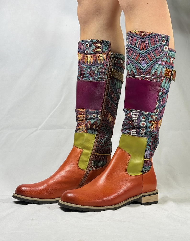 May include: A pair of knee-high boots with a brown leather upper and a patterned fabric shaft. The fabric is a mix of blue, green, purple, and orange colors with geometric designs. The boots have a zipper on the inside of the shaft and a buckle on the outside.