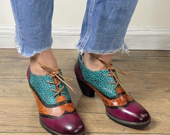 May include: A pair of teal, orange, and purple heeled shoes with lace-up closures. The shoes have a patterned design and a block heel.