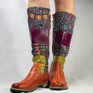 May include: A pair of knee-high boots with a brown leather upper and a colorful patterned fabric shaft. The boots have a side zipper and a low heel.