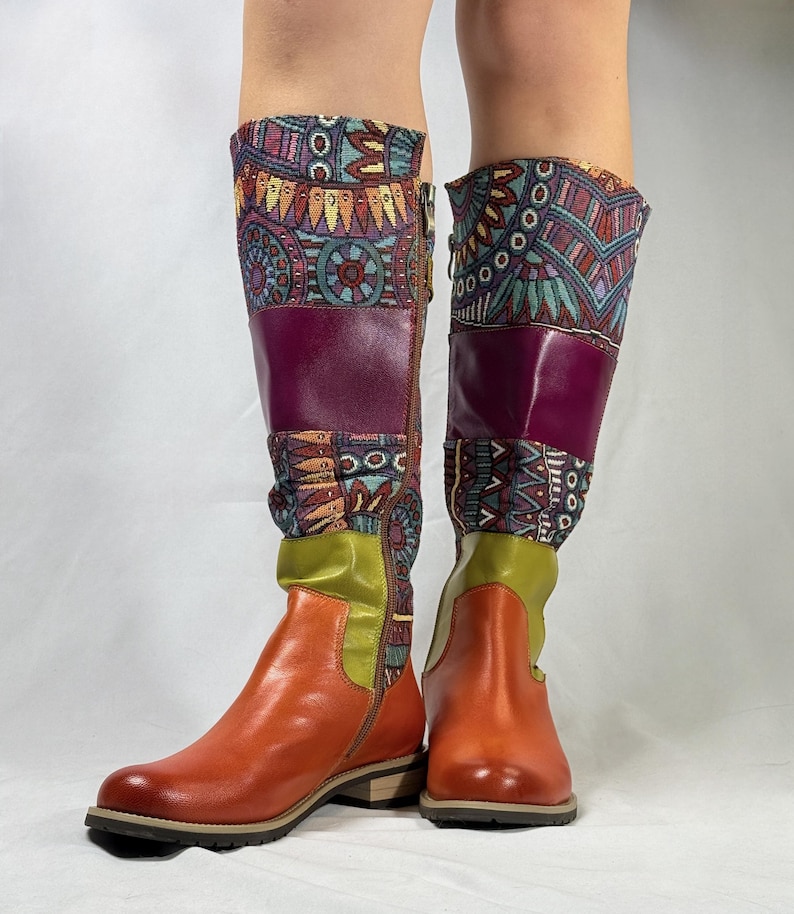 May include: A pair of knee-high boots with a brown leather upper and a colorful patterned fabric shaft. The boots have a side zipper and a low heel.