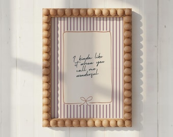 May include: A rectangular wall art print in a light wood beaded frame. The print features a cream background with vertical purple stripes, a central rectangular border, and the text: I kinda like it when you call me wonderful.