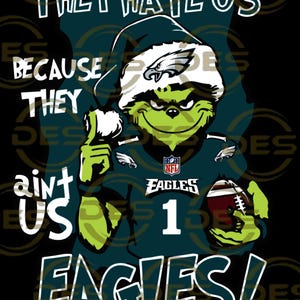 May include: A green Grinch-like character in an Eagles football jersey and a Santa hat, holding a football. Text reads "THEY HATE US BECAUSE THEY AIN'T US EAGLES!" in white and green. The background is black.