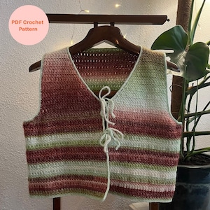 May include: A handmade crochet vest with a V-neck and tie closure. The vest features horizontal stripes in shades of red, green, and cream. The text "PDF Crochet Pattern" is in a circle in the upper left corner.