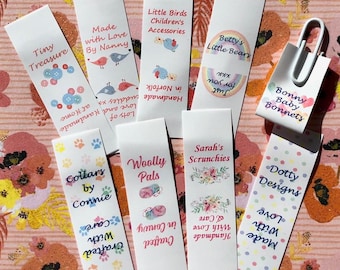 Op de afbeelding: Een verzameling van negen rechthoekige witte papieren labels met diverse merknamen en afbeeldingen, waaronder Tiny Treasure, Made with Love By Nanny, Little Birds Children's Accessories, Betty's Little Bears, Bonny Baby Bonnets, Collars by Connie, Woolly Pals, Sarah's Scrunchies en Dotty Designs.