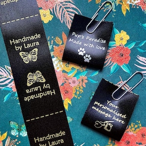 Peut inclure: Étiquettes en tissu noir avec texte doré et motifs de papillons, et un ruban avec le texte "Handmade by Laura". Deux étiquettes sont attachées avec des trombones. L'une dit "Pup's Paradise Made with love" et l'autre "Your personalised message here".