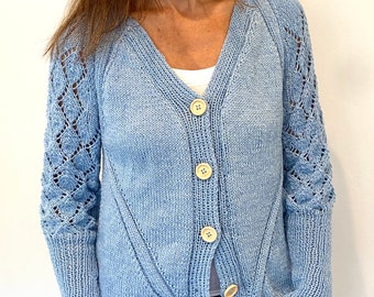 May include: A light blue knitted cardigan with a V-neck and button closure. The cardigan has a lace pattern on the sleeves and a textured knit throughout.
