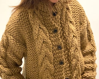May include: A brown cable knit cardigan with a button fastening. The cardigan has a chunky knit texture and a relaxed fit.