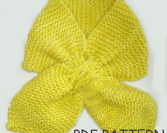 May include: A bright yellow knitted scarf with a bow design. The scarf is made with a simple stitch pattern and has a soft, textured look. The image includes the text "PDF PATTERN".
