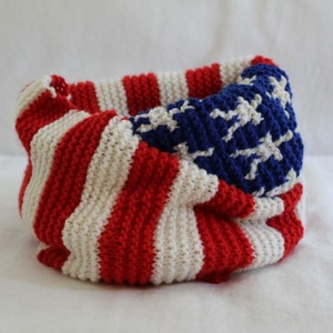 May include: A knitted scarf in red, white, and blue, featuring a design resembling the American flag.