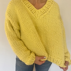 Puede incluir: Un suéter de punto grueso de color amarillo brillante con cuello en V.