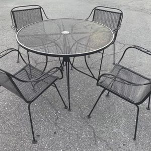 May include: A black metal patio set with a round table and four chairs. The table and chairs have a mesh design.