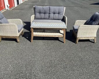 May include: A wicker patio furniture set with a loveseat, two chairs, and a coffee table. The furniture is white with gray cushions.