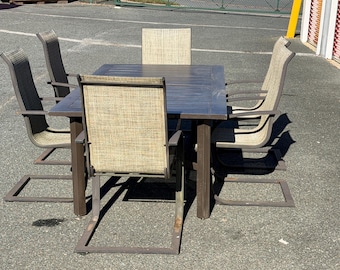 May include: A rectangular outdoor dining table with a dark brown metal frame and a slatted top, accompanied by four matching chairs featuring dark brown metal cantilever bases and beige woven fabric seats and backrests.