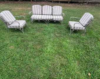 May include: A patio furniture set consisting of one three-seat sofa and two matching armchairs. Each piece features a white metal frame with decorative scrollwork and cushions upholstered in a white fabric with thin vertical black stripes.