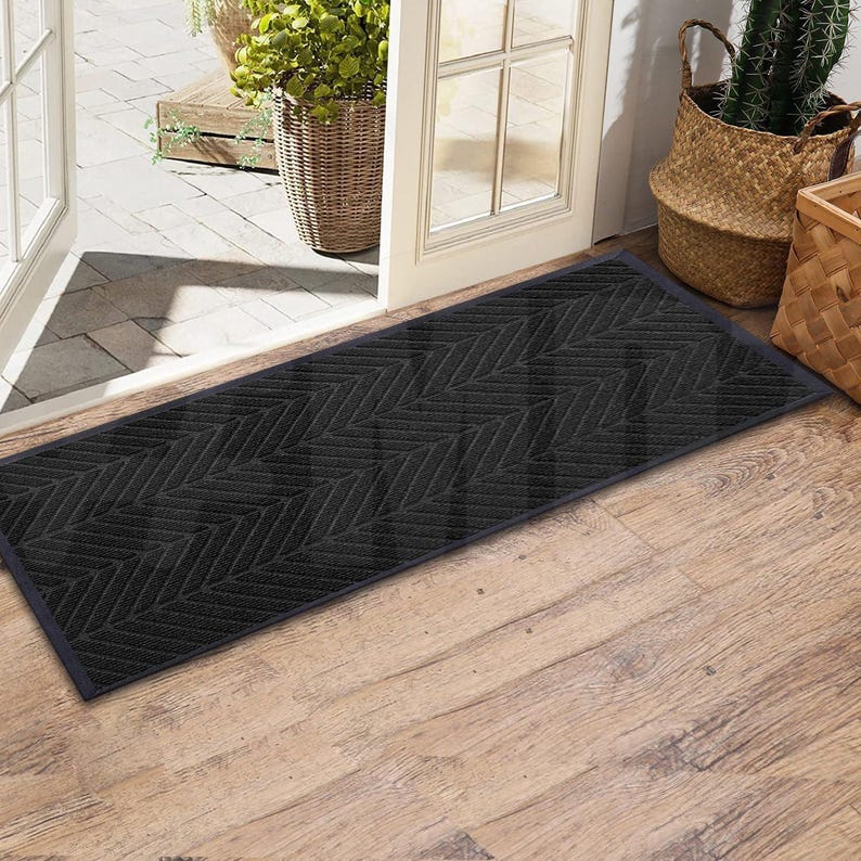 May include: A black doormat with a herringbone pattern. The doormat is made of a durable material and is designed to trap dirt and moisture.